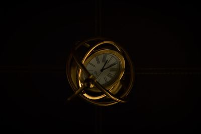 Low angle view of illuminated lamp hanging against black background