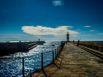 Pier on sea against cloudy sky