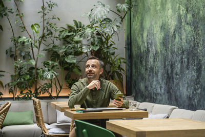 Portrait of man looking away while sitting on table