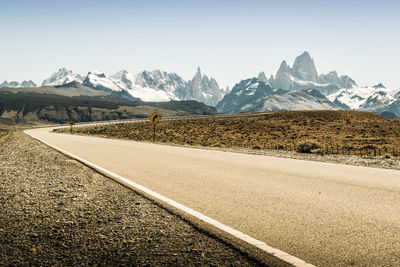 Road by mountains against clear sky