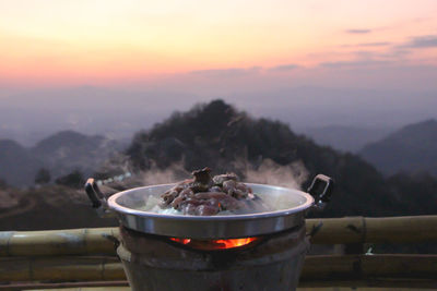 High angle view of meat on barbecue grill against sky during sunset