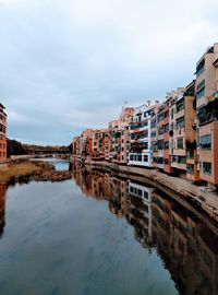 Buildings by river against sky in city