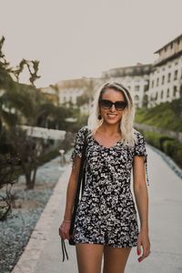 Portrait of young woman wearing sunglasses standing outdoors