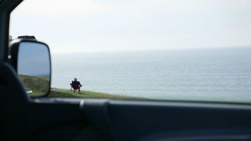 Woman standing by sea against sky