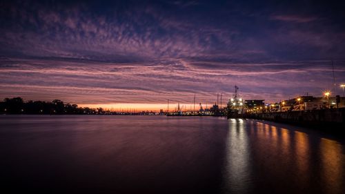 Illuminated river against sky at sunset