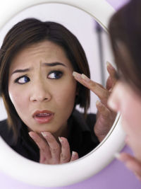 Woman looking at her reflection in mirror at home