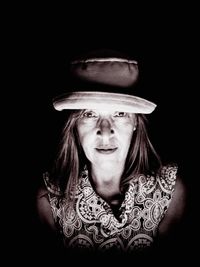 Portrait of woman wearing hat against black background