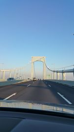 Cars moving on bridge against blue sky