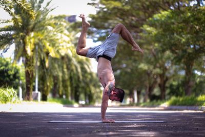 Full length of man doing handstand on road