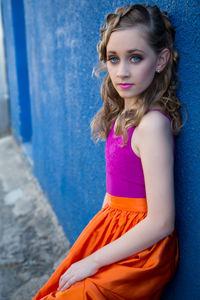 Side view portrait of girl with make-up leaning on blue wall