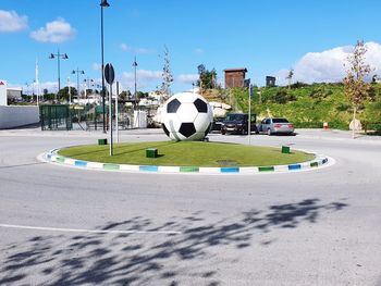 Soccer ball on street light in city against sky