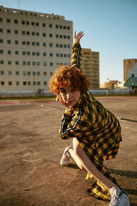 Redhead curly young female dancing in an empty parking lot