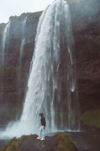 Rear view of a woman standing against waterfall