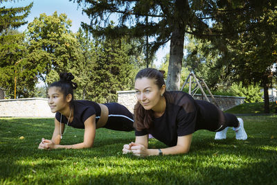 Girl in sportswear on a sunny summer day on the embankment in the park doing fitness and stretching