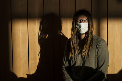 Portrait of man wearing mask standing against wall