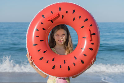 A young girl looks through an inflatable ring on the beach. summer holidays on the sea coast.