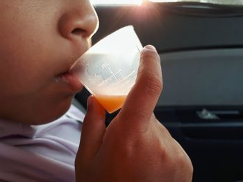 Midsection of boy drinking syrup in car