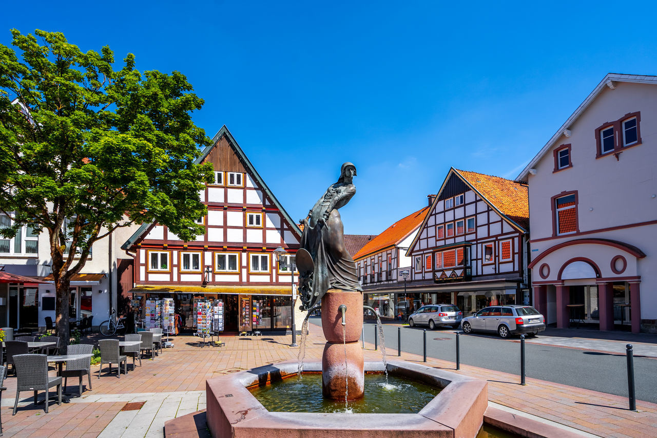 STATUE AMIDST BUILDINGS AGAINST SKY