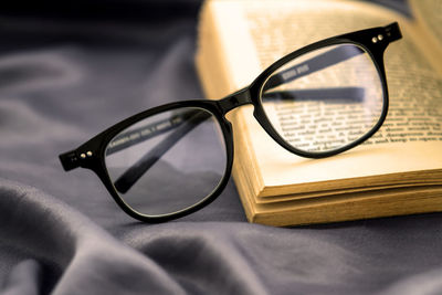 Close-up of book with eyeglasses on table