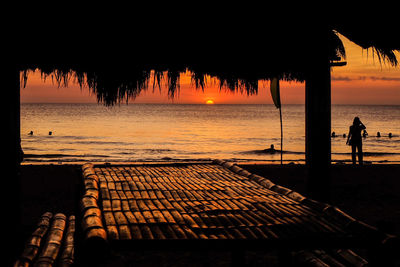 Silhouette people at beach against sky during sunset