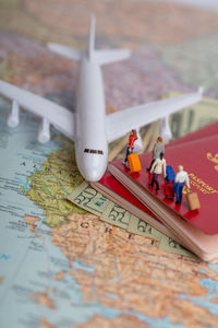 Close-up of figurines boarding airplane model on map and passports