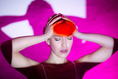 Portrait of young woman with pink petals on wall