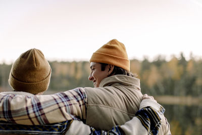 Rear view of male friends wearing knit hat with arms around each other