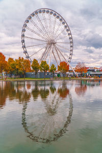 Ferris wheel by lake against sky