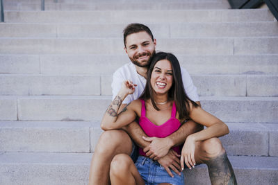 Happy young couple sitting on staircase