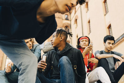 Male friends with mobile phones sitting in city