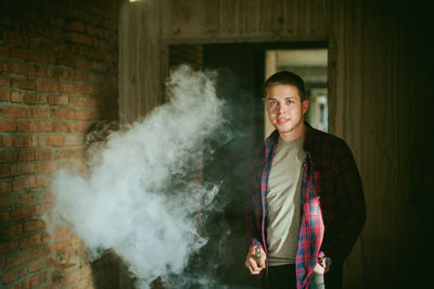 Portrait of young man smoking electronic cigarette