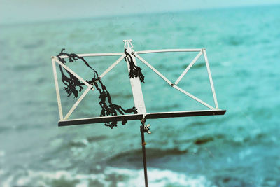 Close-up of metallic book stand against sea