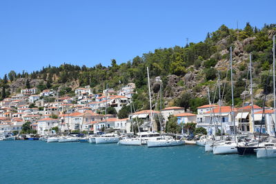 Sailboats in sea by buildings against clear sky
