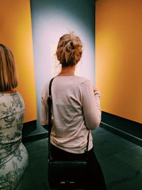 Rear view of woman standing against wall in museum