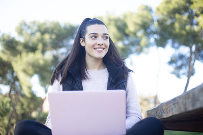 Portrait of smiling young woman using smart phone outdoors