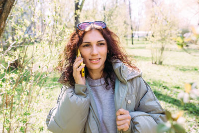 Portrait of young woman standing against plants