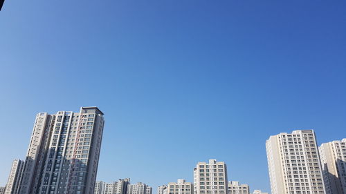 Low angle view of modern buildings against clear blue sky