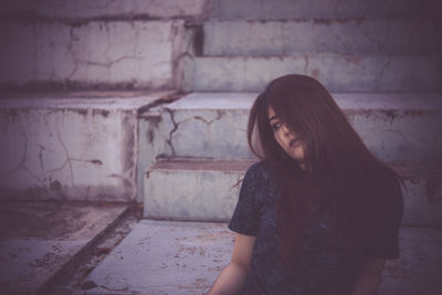 Portrait of woman sitting against wall