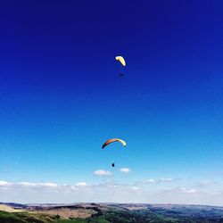 Low angle view of paragliding against blue sky