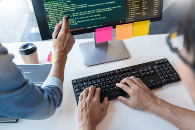 Midsection of computer programmers using computer on office desk