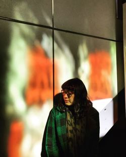 Portrait of young woman standing against window