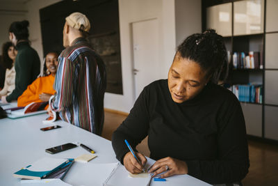 Mature female student writing while studying in community college