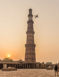 Low angle view of airplane in flight over tower