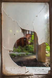 Close-up of broken window on wall of building