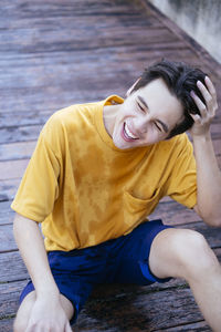 High angle view of smiling young woman sitting on boardwalk