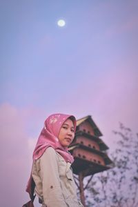 Low angle view of woman standing against pink sky