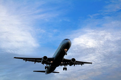 Low angle view of airplane flying in blue sky