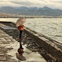 Rear view of woman with umbrella on water