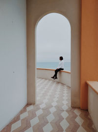 Woman sitting in corridor against sea