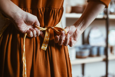 Potter woman getting ready for work by putting on apron person